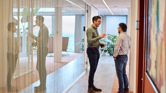 Two colleagues confer briefly in the corridor