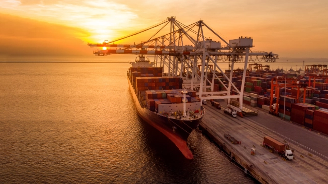 Crane loading cargo container at sunset