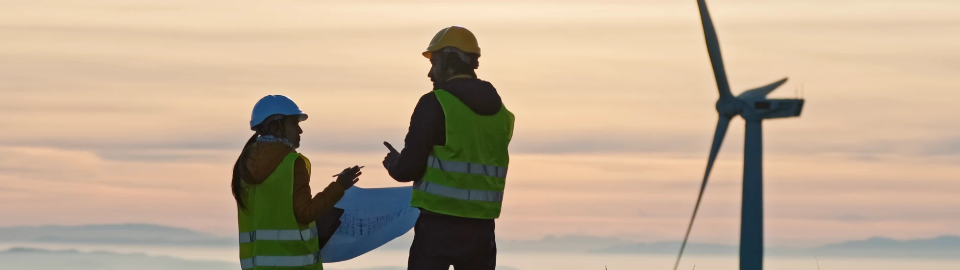Two wind turbine engineers at sunset