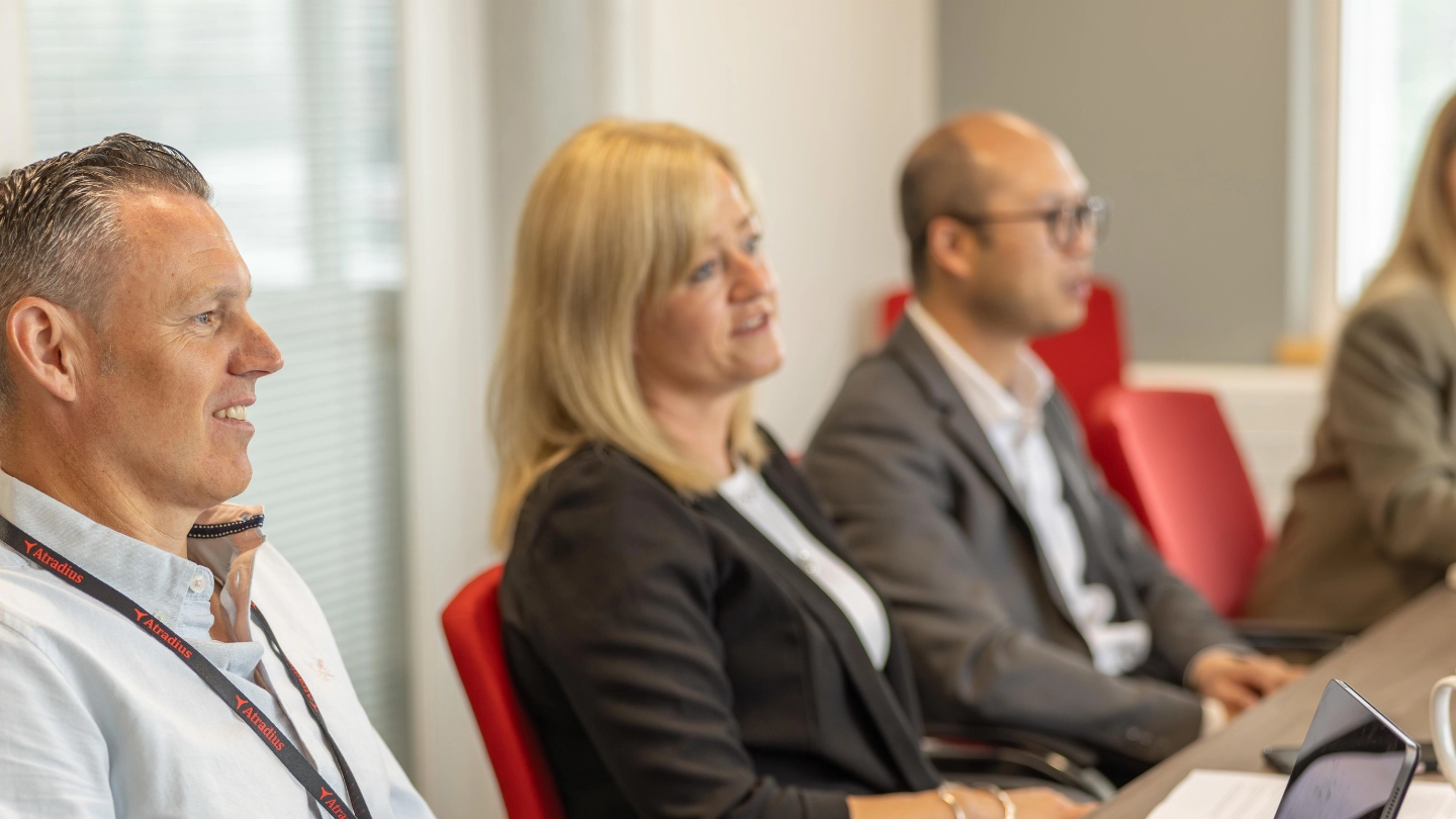 Two women and men in a large meeting room