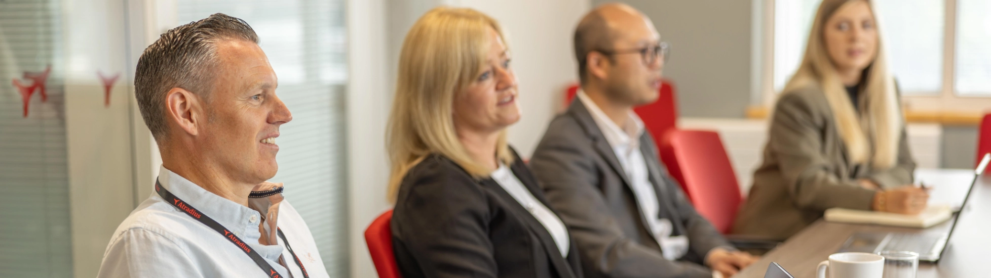 Two women and men in a large meeting room